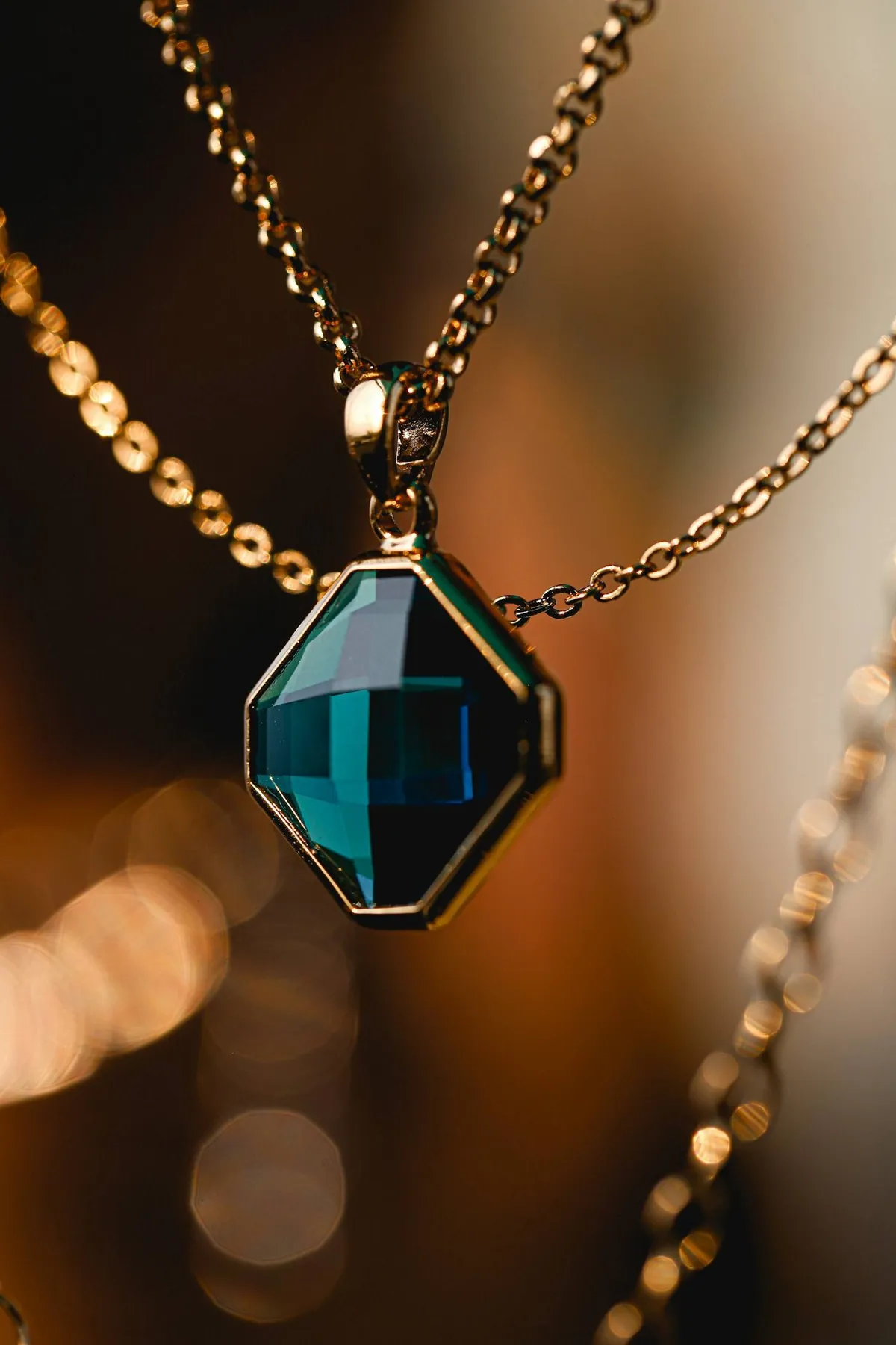 Pendentif serti d'une pierre verte émeraude sur une chaîne dorée