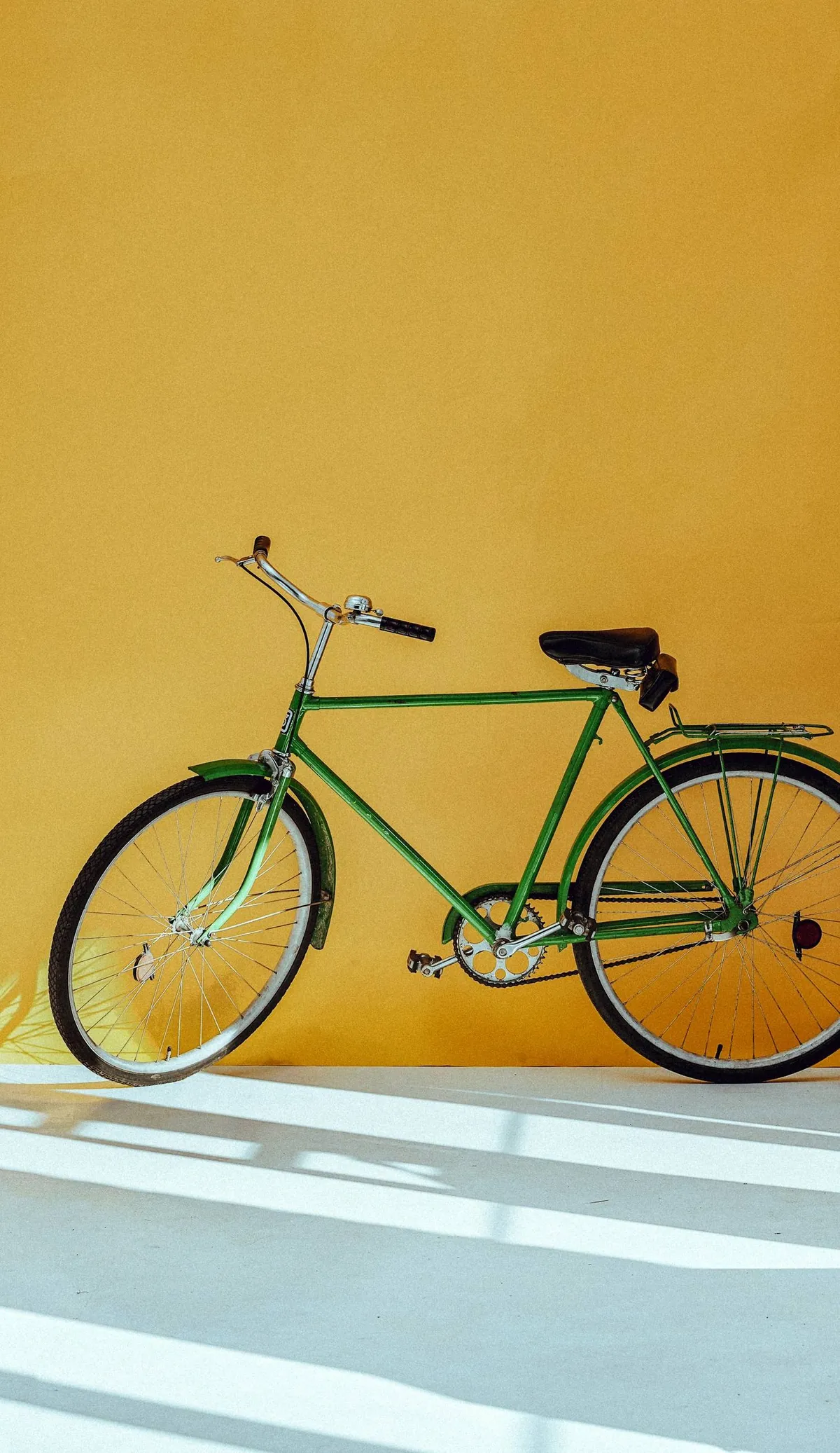 Vélo vert appuyé contre un mur jaune vif